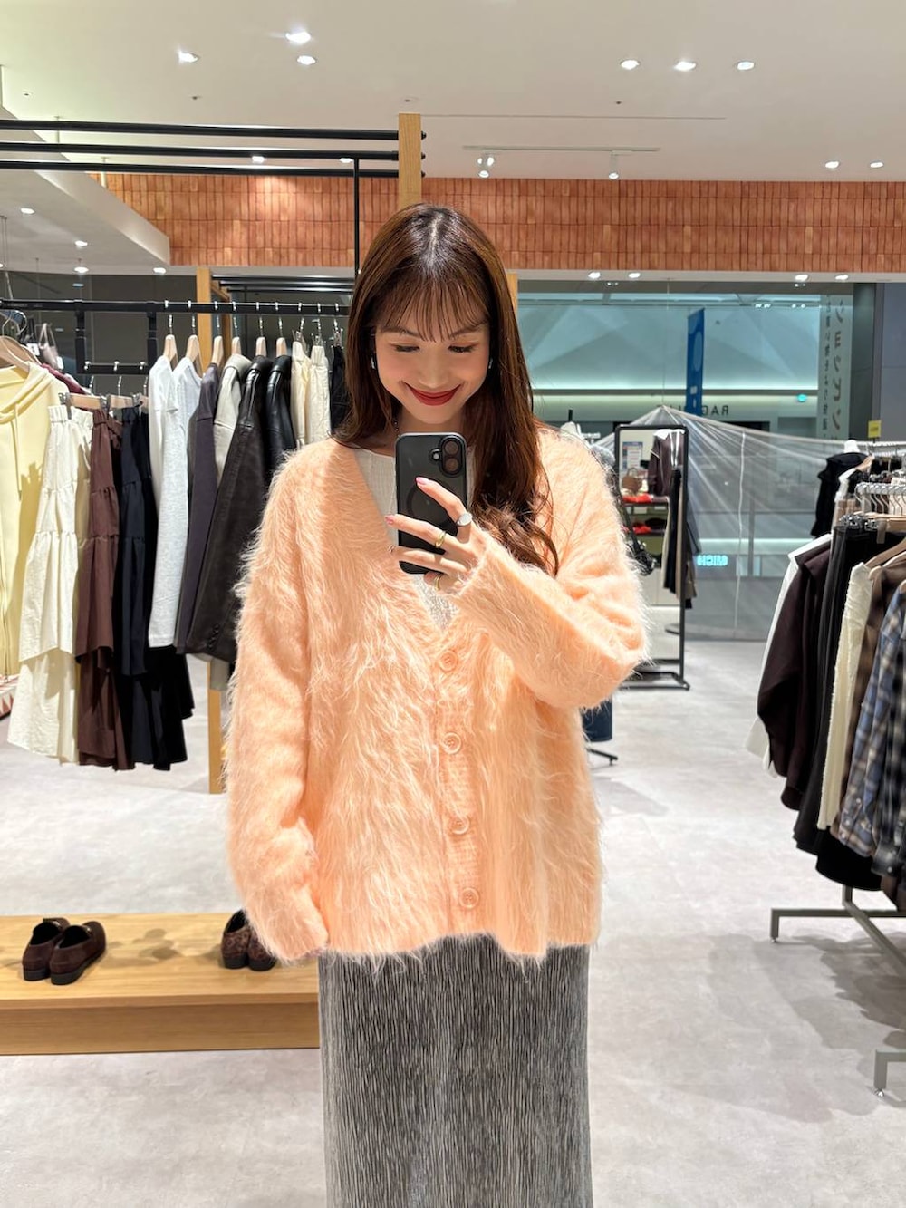 ベージュ系のTシャツ/カットソー、ホワイト系のブーツ、グレー系のスカートを着用したレディースの秋コーディネートの2枚目の写真