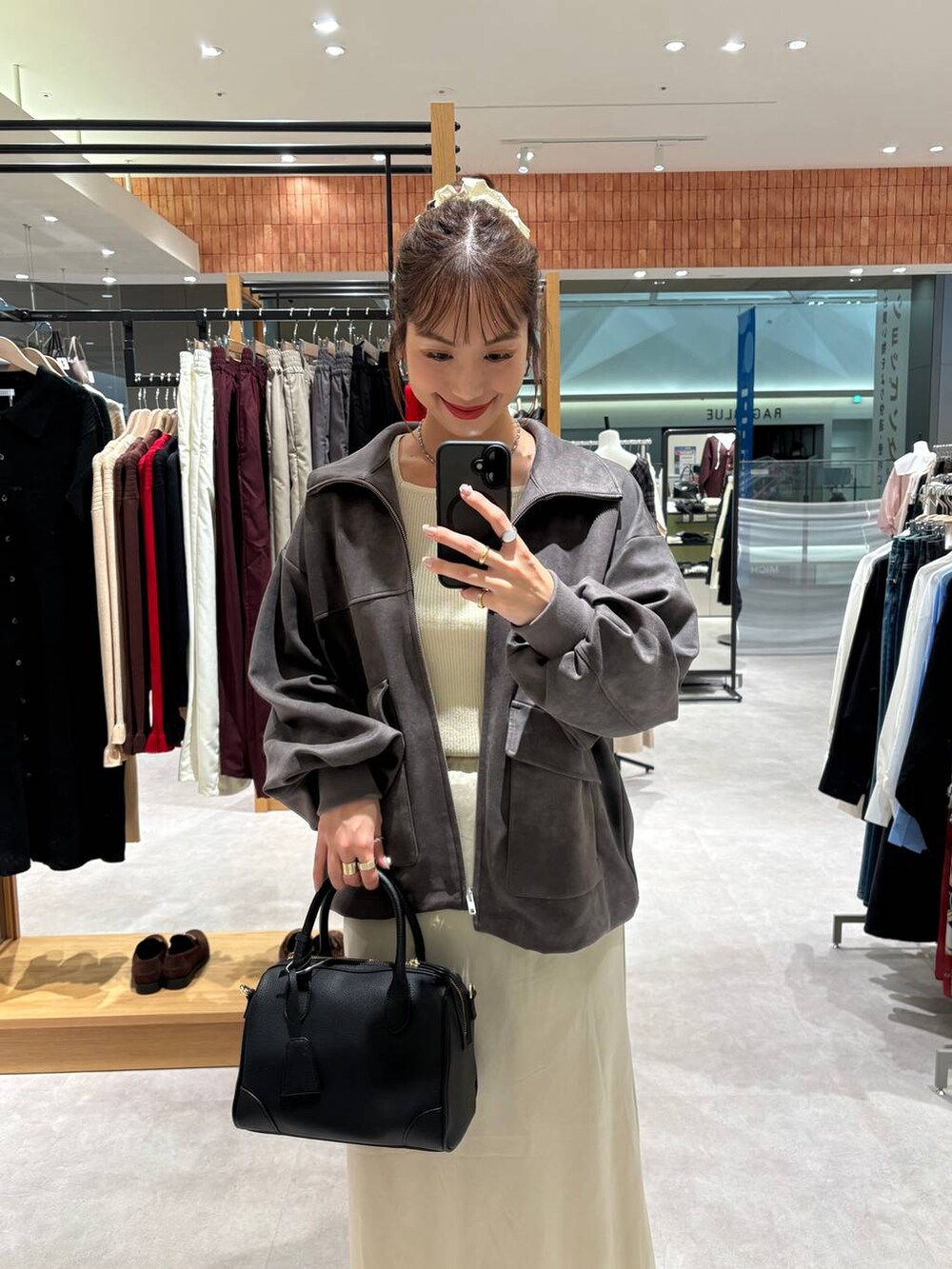 ホワイト系のニット/セーター、ブラック系のショルダーバッグ、グレー系のブルゾンを着用したレディースの秋コーディネートの2枚目の写真