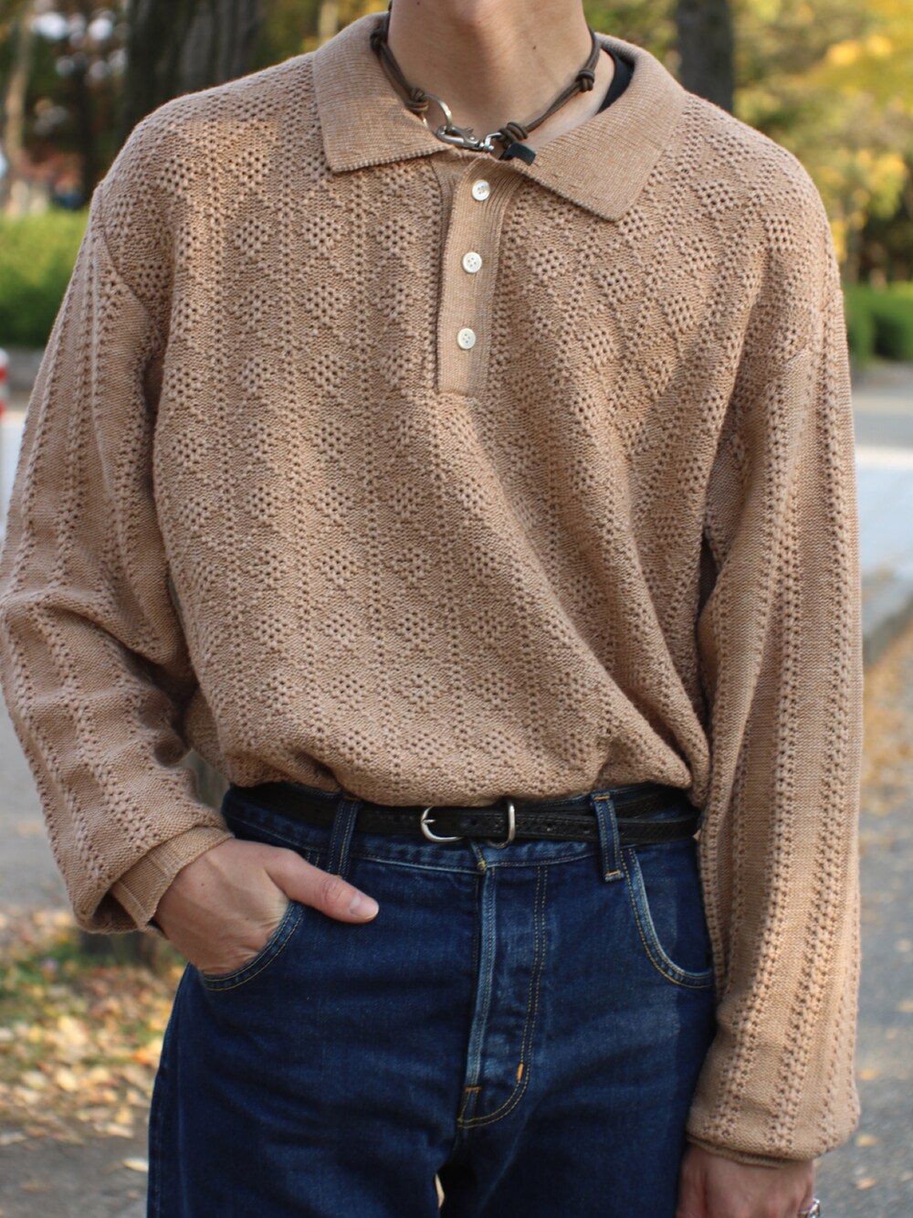 ブルー系のデニムパンツ、ブラック系のブーツ、ブラック系のハンドバッグを着用したメンズの秋コーディネートの3枚目の写真