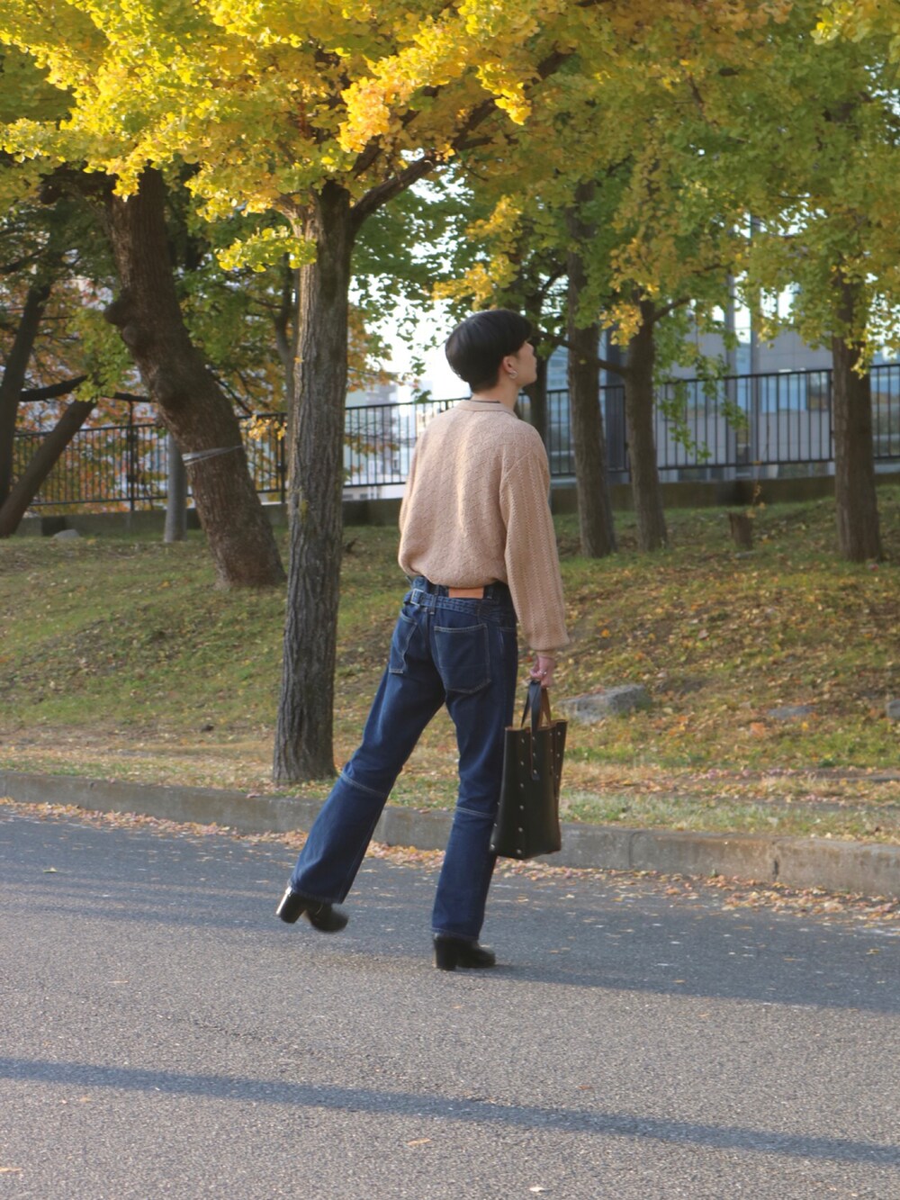 ブルー系のデニムパンツ、ブラック系のブーツ、ブラック系のハンドバッグを着用したメンズの秋コーディネートの5枚目の写真