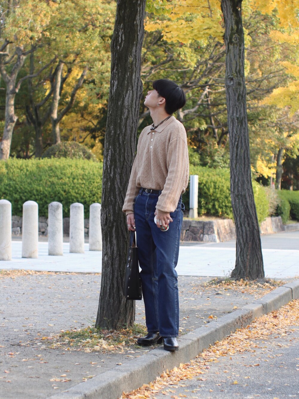 ブルー系のデニムパンツ、ブラック系のブーツ、ブラック系のハンドバッグを着用したメンズの秋コーディネートの2枚目の写真