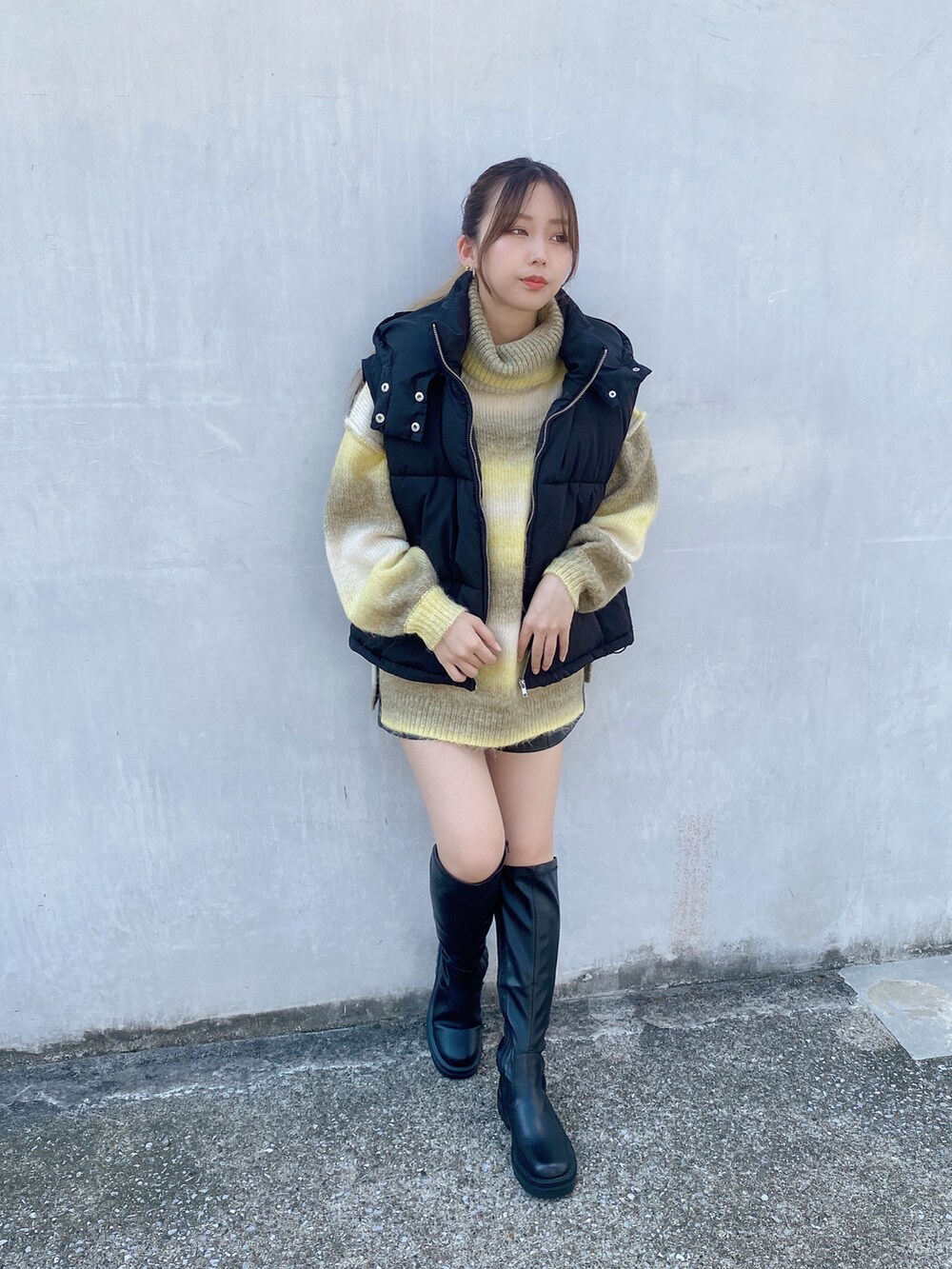 イエロー系のニット/セーター、ブラック系のダウンベストを着用したレディースの秋コーディネートの2枚目の写真