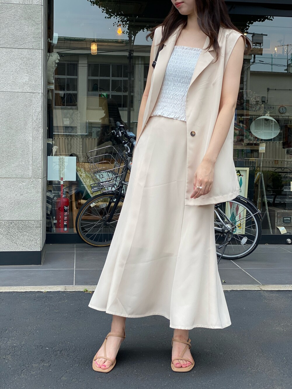 ベージュ系のスカート、ホワイト系のキャミソール、ブラック系のショルダーバッグを着用したレディースの夏コーディネートの2枚目の写真