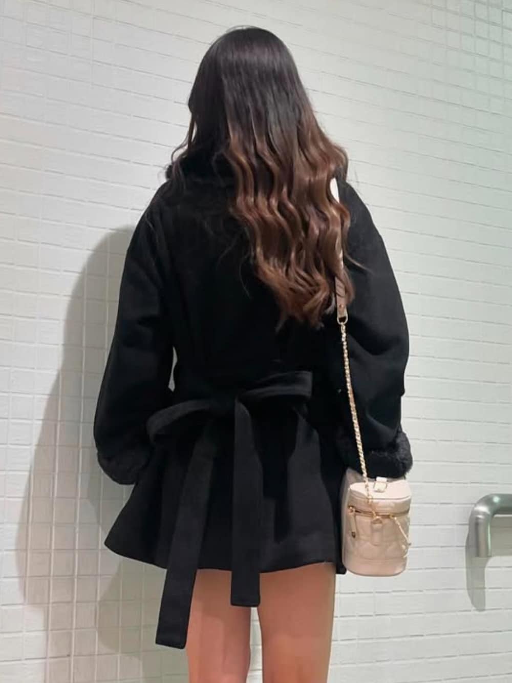 ブラック系のノーカラーコートを着用したレディースの冬コーディネートの2枚目の写真