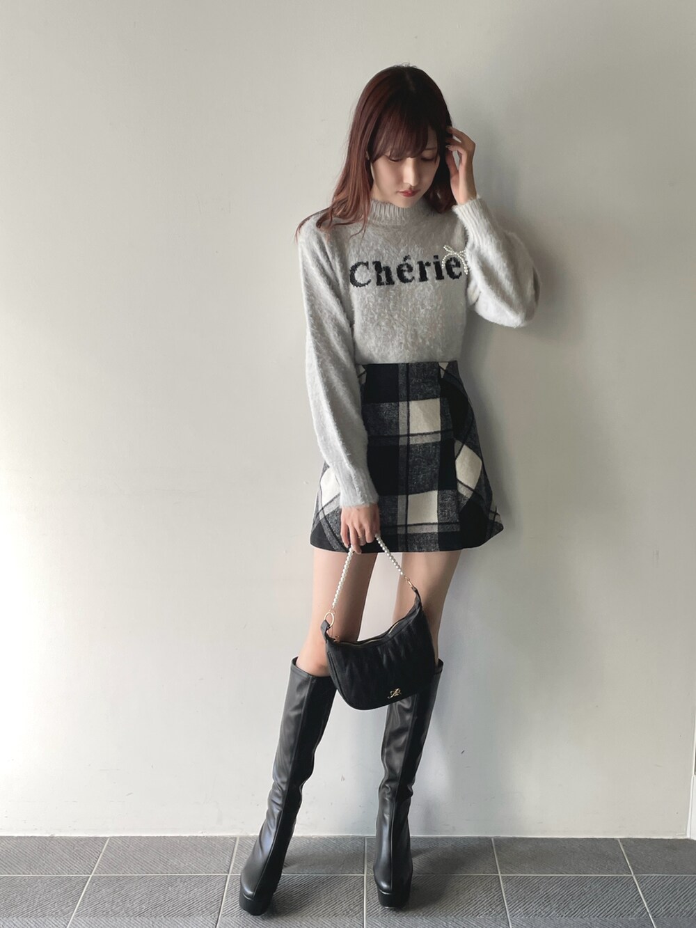 グレー系のニット/セーター、ブラック系のスカート、ブラック系のショルダーバッグを着用したレディースの冬コーディネートの2枚目の写真