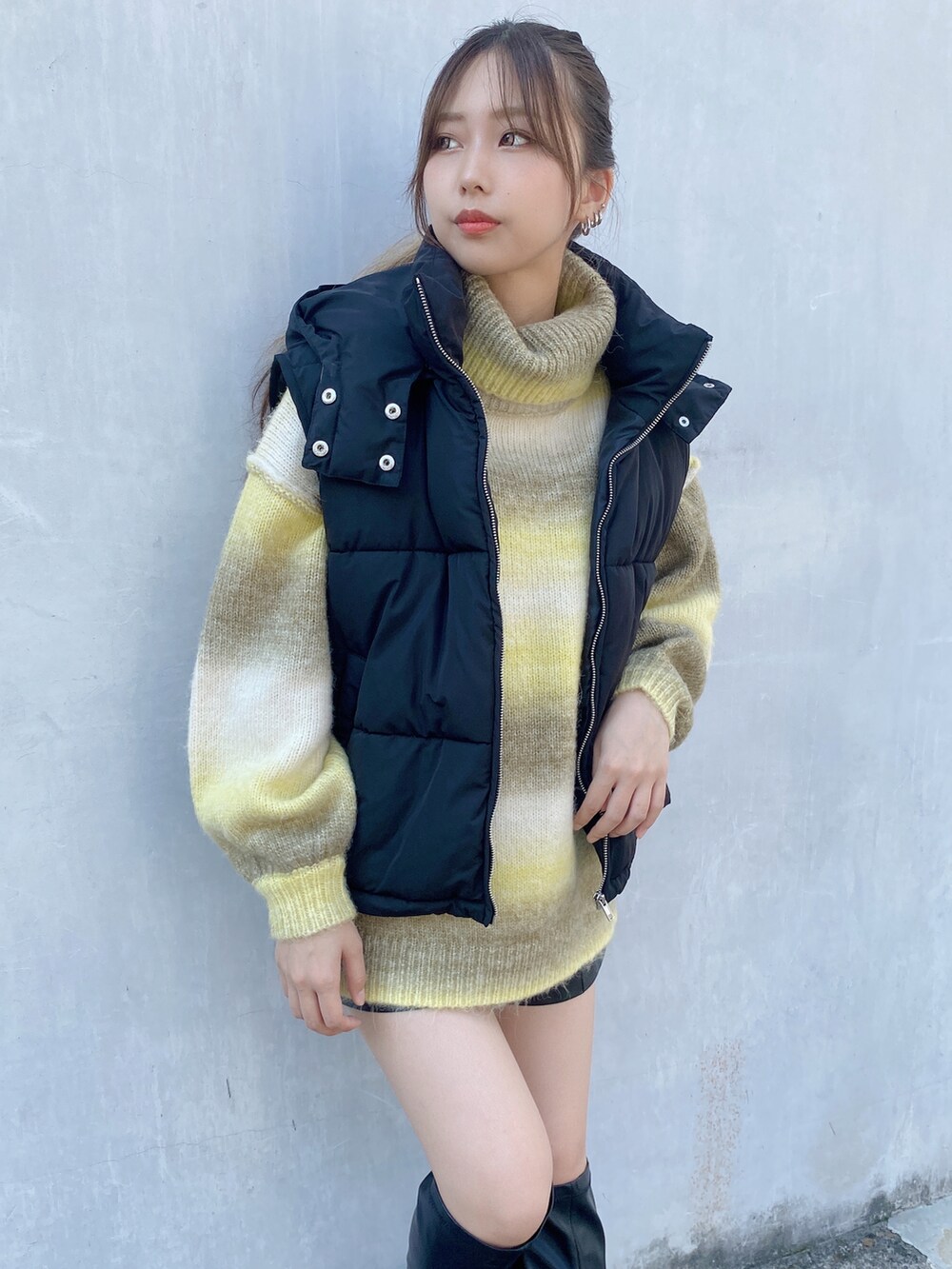 イエロー系のニット/セーター、ブラック系のダウンベストを着用したレディースの秋コーディネートの3枚目の写真