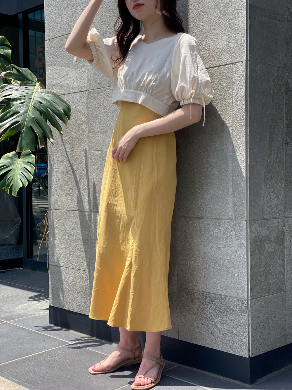 イエロー系のワンピースを着用したレディースの夏コーディネートの2枚目の写真