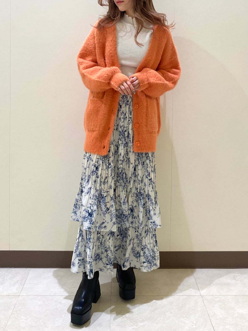 オレンジ系のカーディガン/ボレロ、ブルー系のスカートを着用したレディースの冬コーディネートの3枚目の写真