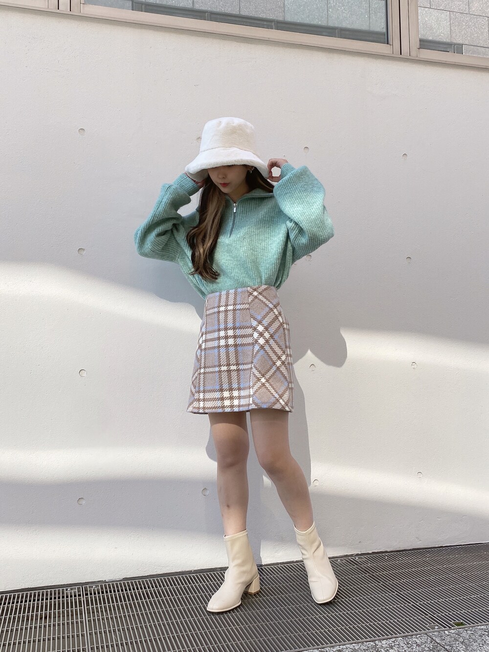 グリーン系のニット/セーター、ベージュ系のスカートを着用したレディースの冬コーディネートの2枚目の写真