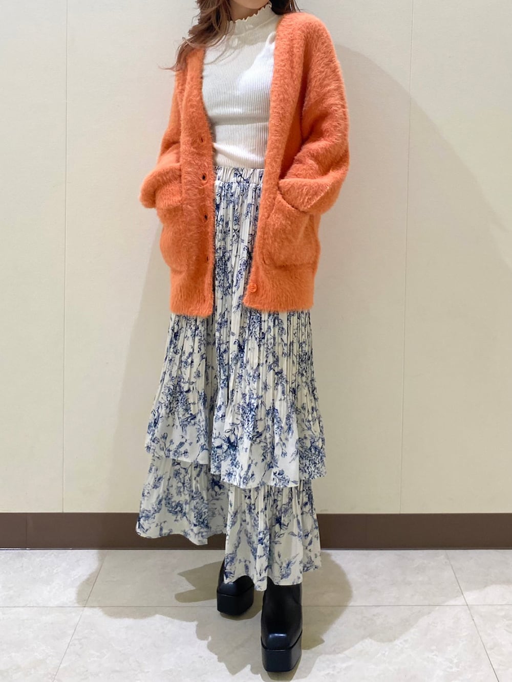 オレンジ系のカーディガン/ボレロ、ブルー系のスカートを着用したレディースの冬コーディネートの4枚目の写真