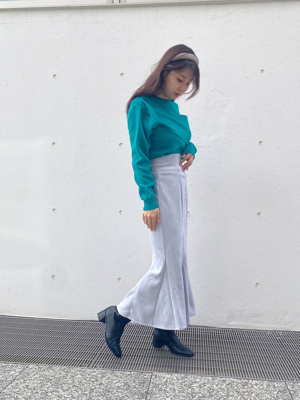 グリーン系のニット/セーター、ブルー系のスカートを着用したレディースの冬コーディネートの2枚目の写真