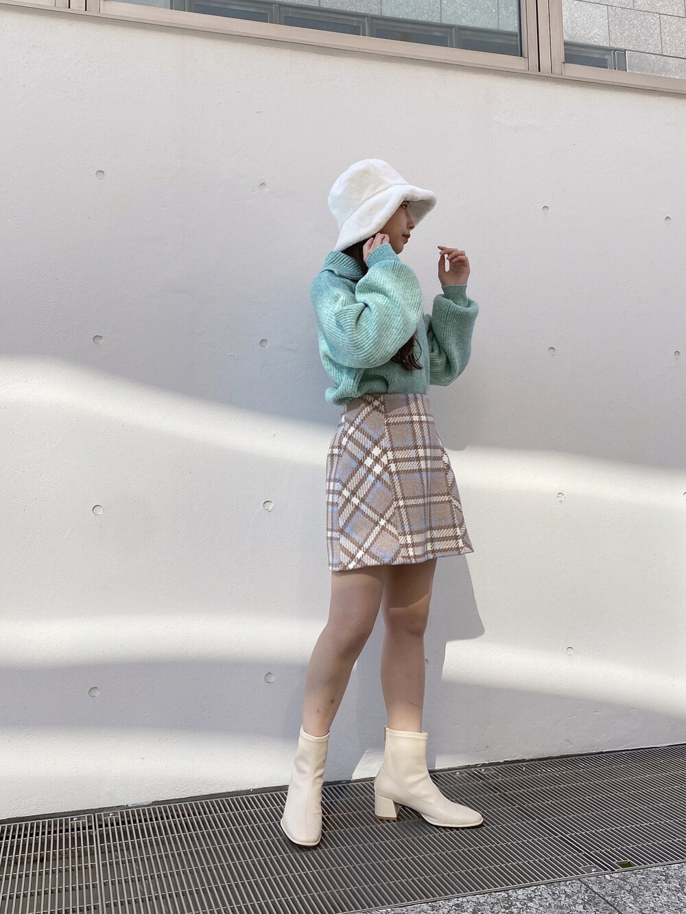 グリーン系のニット/セーター、ベージュ系のスカートを着用したレディースの冬コーディネートの4枚目の写真