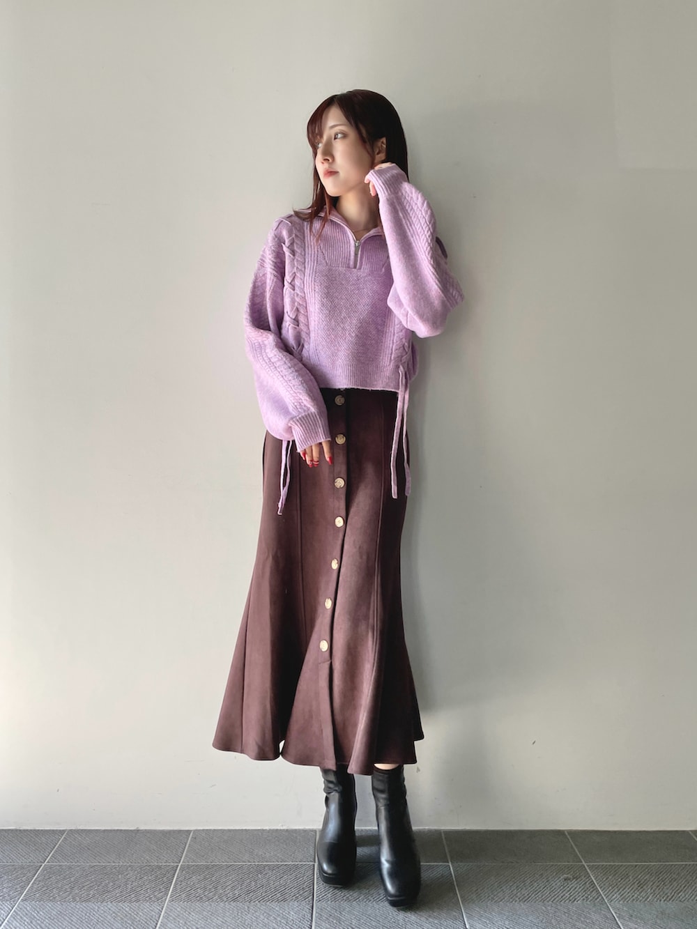 パープル系のニット/セーター、ブラウン系のスカート、ブラック系のブーツを着用したレディースの冬コーディネートの2枚目の写真