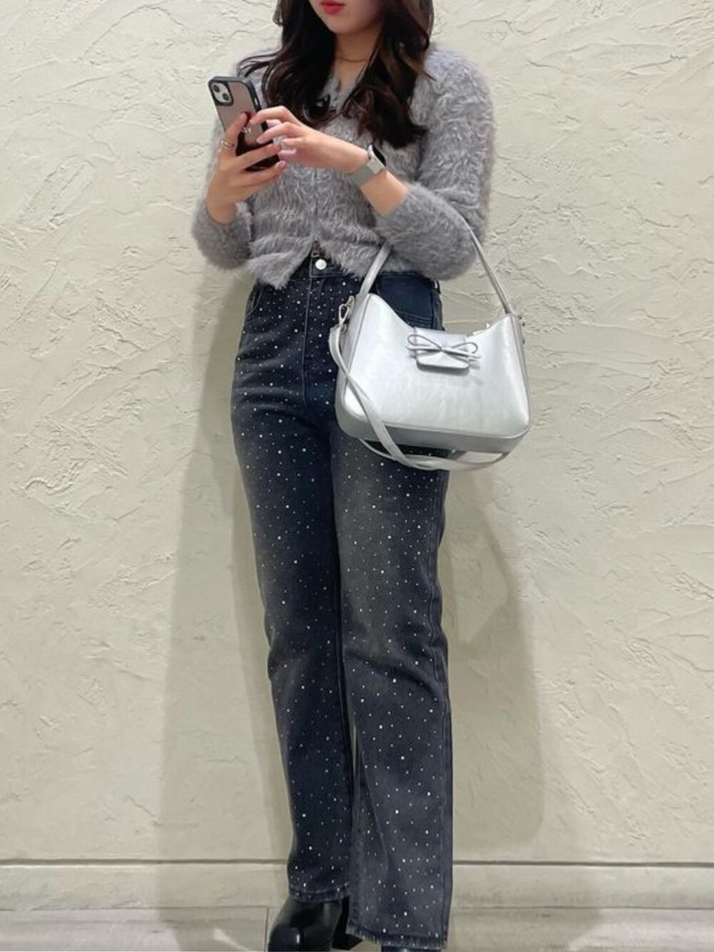 グレー系のニット/セーター、ブルー系のデニムパンツ、グレー系のショルダーバッグを着用したレディースの秋コーディネートの2枚目の写真