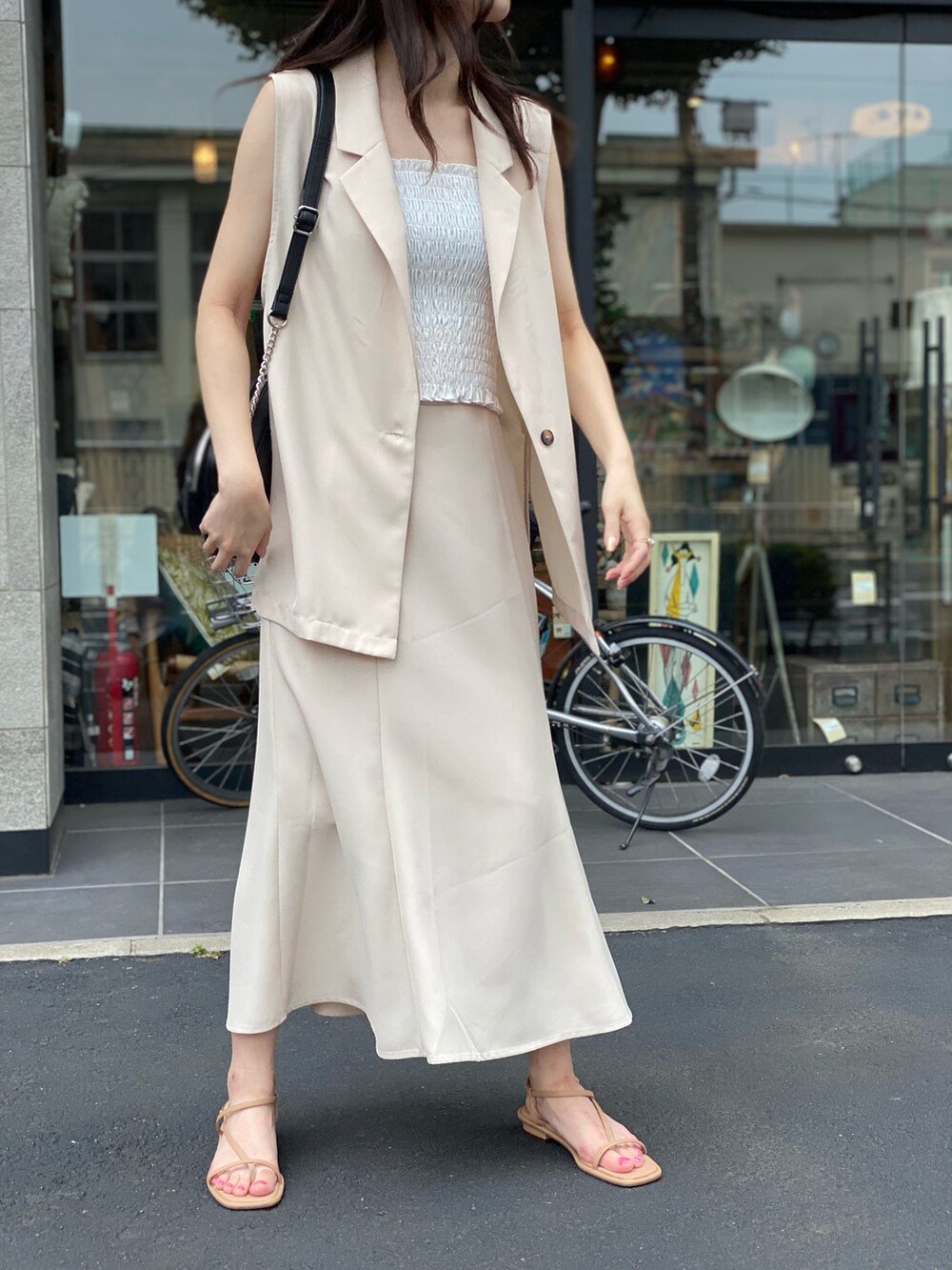 ベージュ系のスカート、ホワイト系のキャミソール、ブラック系のショルダーバッグを着用したレディースの夏コーディネートの3枚目の写真