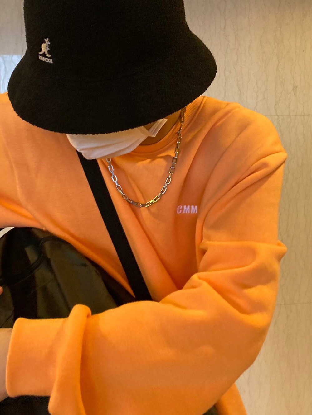 オレンジ系のスウェット、ブラック系のデニムパンツ、グレー系のスニーカーを着用したメンズの冬コーディネートの2枚目の写真