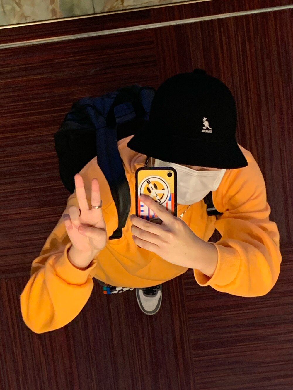 オレンジ系のスウェット、ブラック系のデニムパンツ、グレー系のスニーカーを着用したメンズの冬コーディネートの4枚目の写真