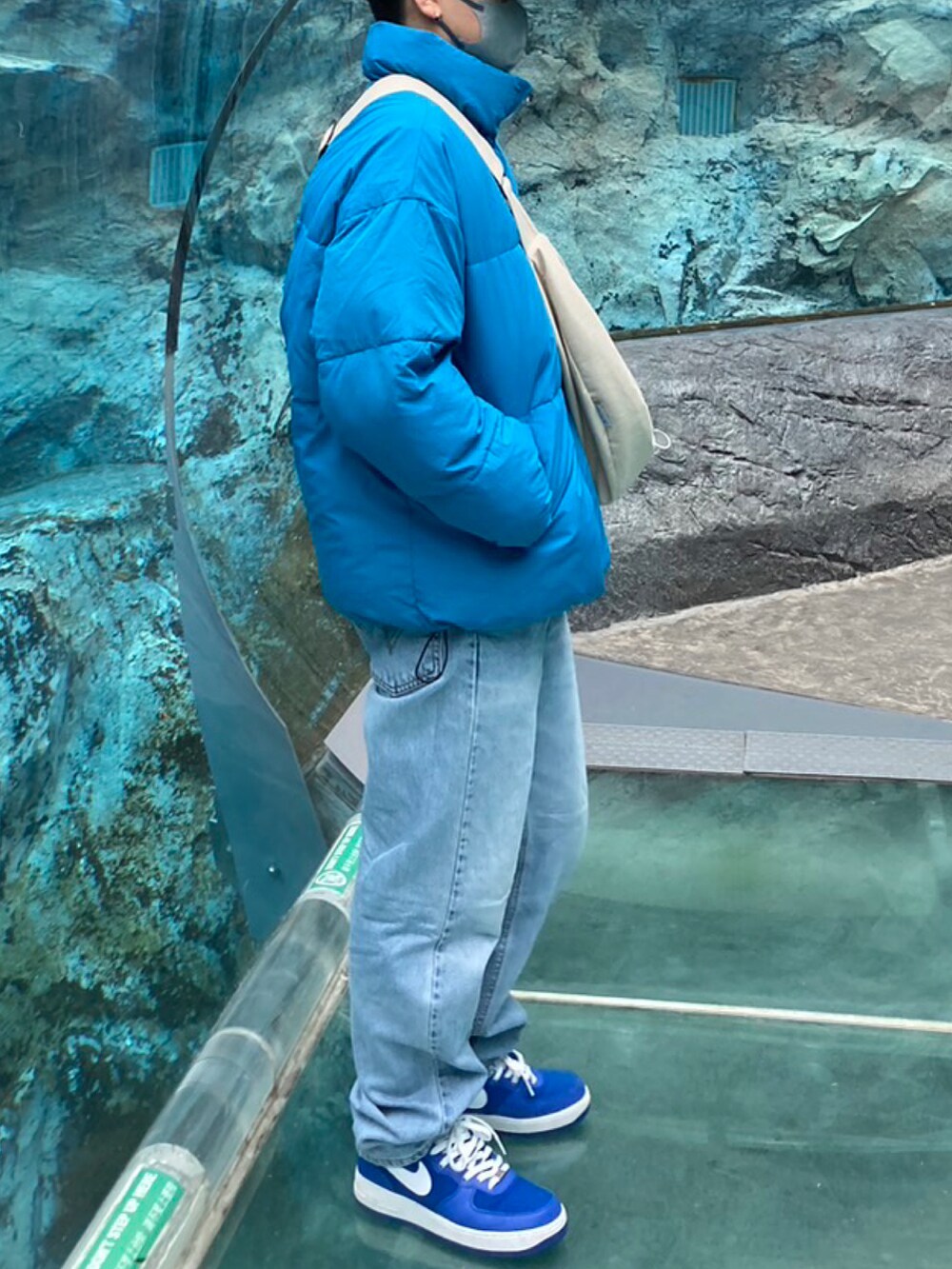 ブラック系のダウンジャケット/コート、ホワイト系のショルダーバッグ、ブルー系のデニムパンツを着用したメンズの冬コーディネートの3枚目の写真