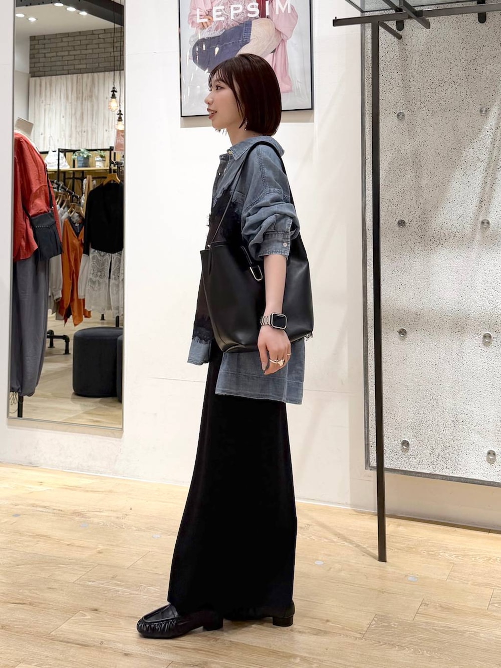 ブラック系のスカート、ブルー系のシャツ/ブラウス、ブラック系のトートバッグを着用したレディースの春コーディネートの2枚目の写真