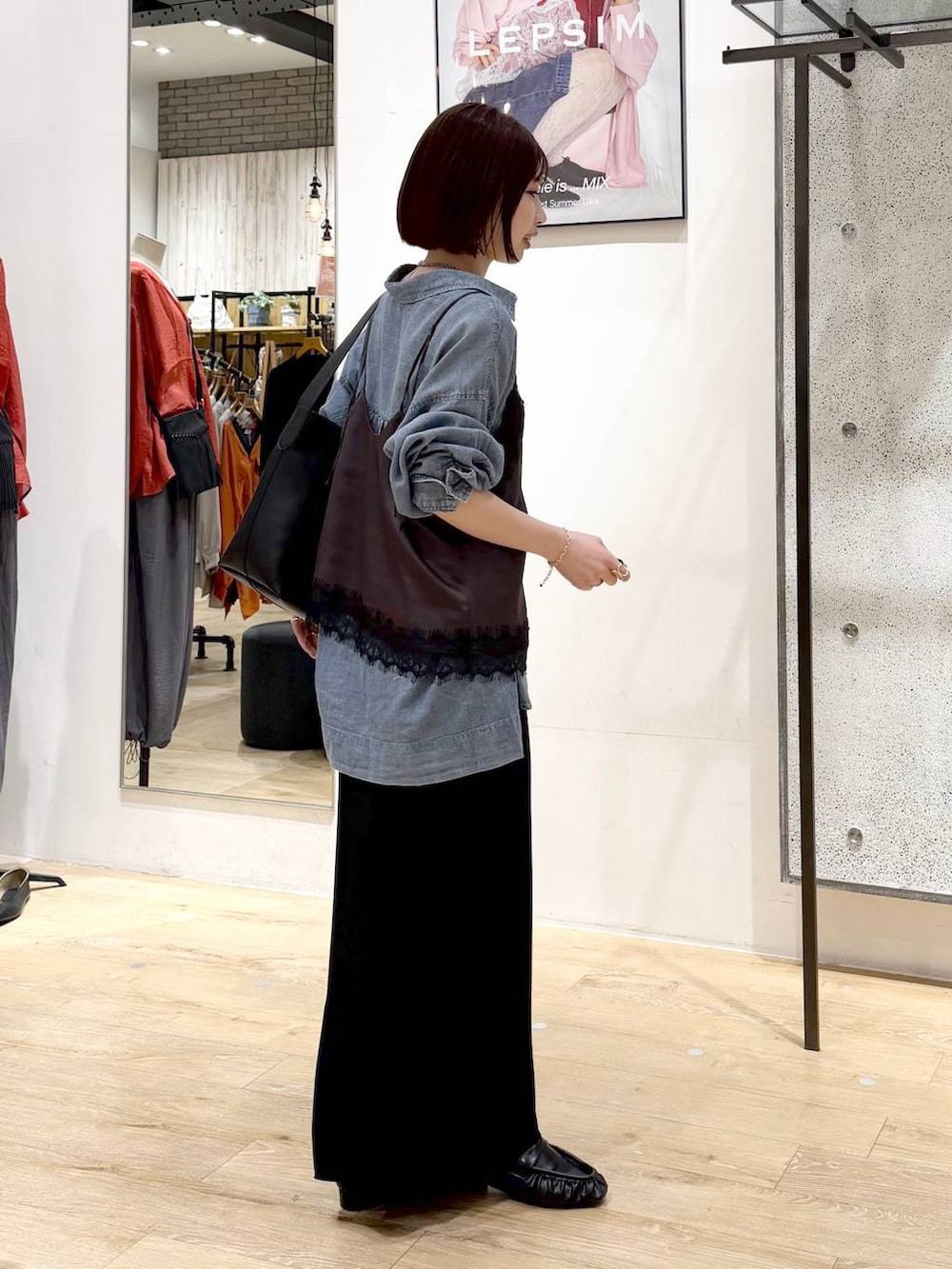 ブラック系のスカート、ブルー系のシャツ/ブラウス、ブラック系のトートバッグを着用したレディースの春コーディネートの4枚目の写真