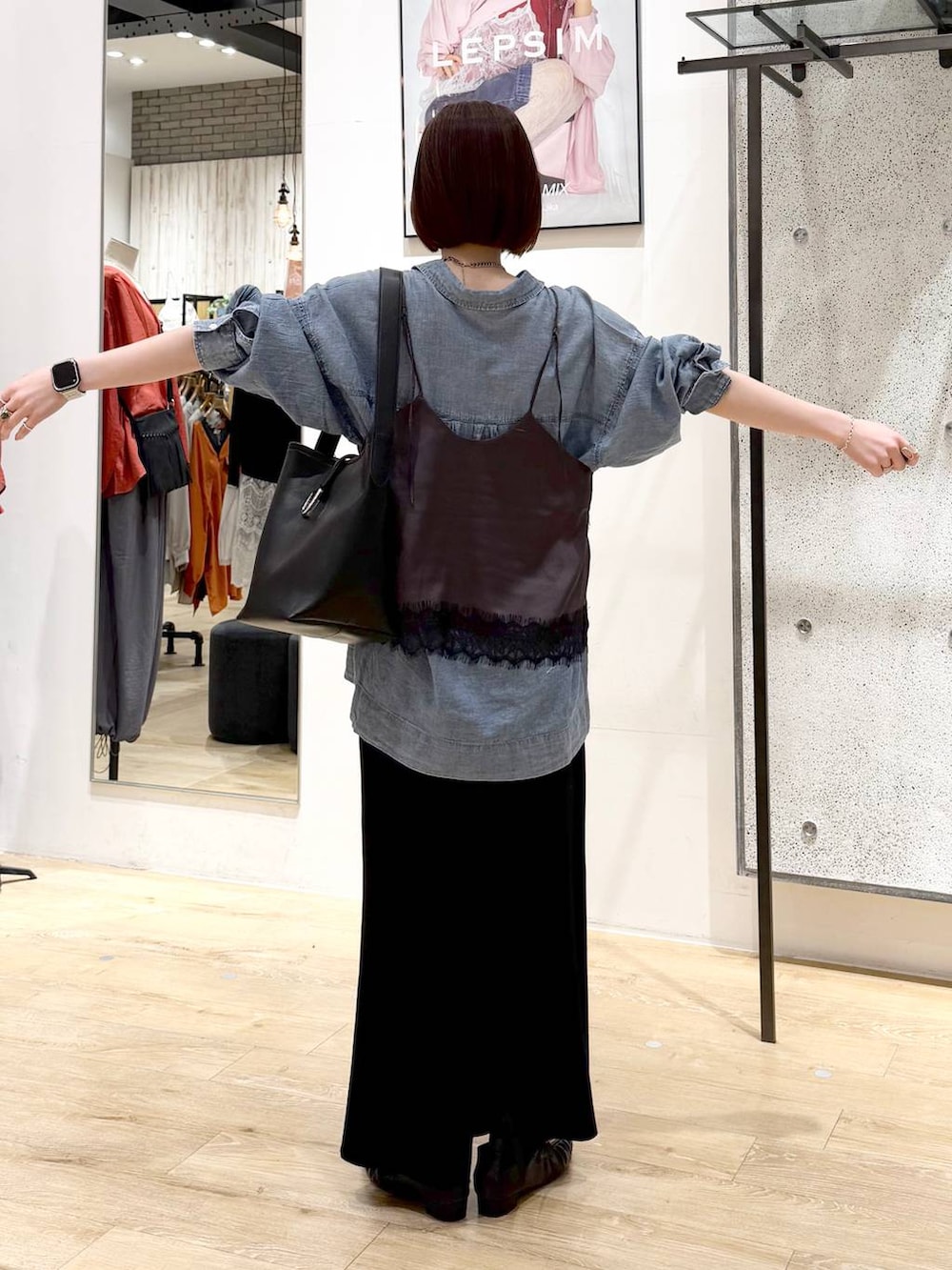 ブラック系のスカート、ブルー系のシャツ/ブラウス、ブラック系のトートバッグを着用したレディースの春コーディネートの3枚目の写真