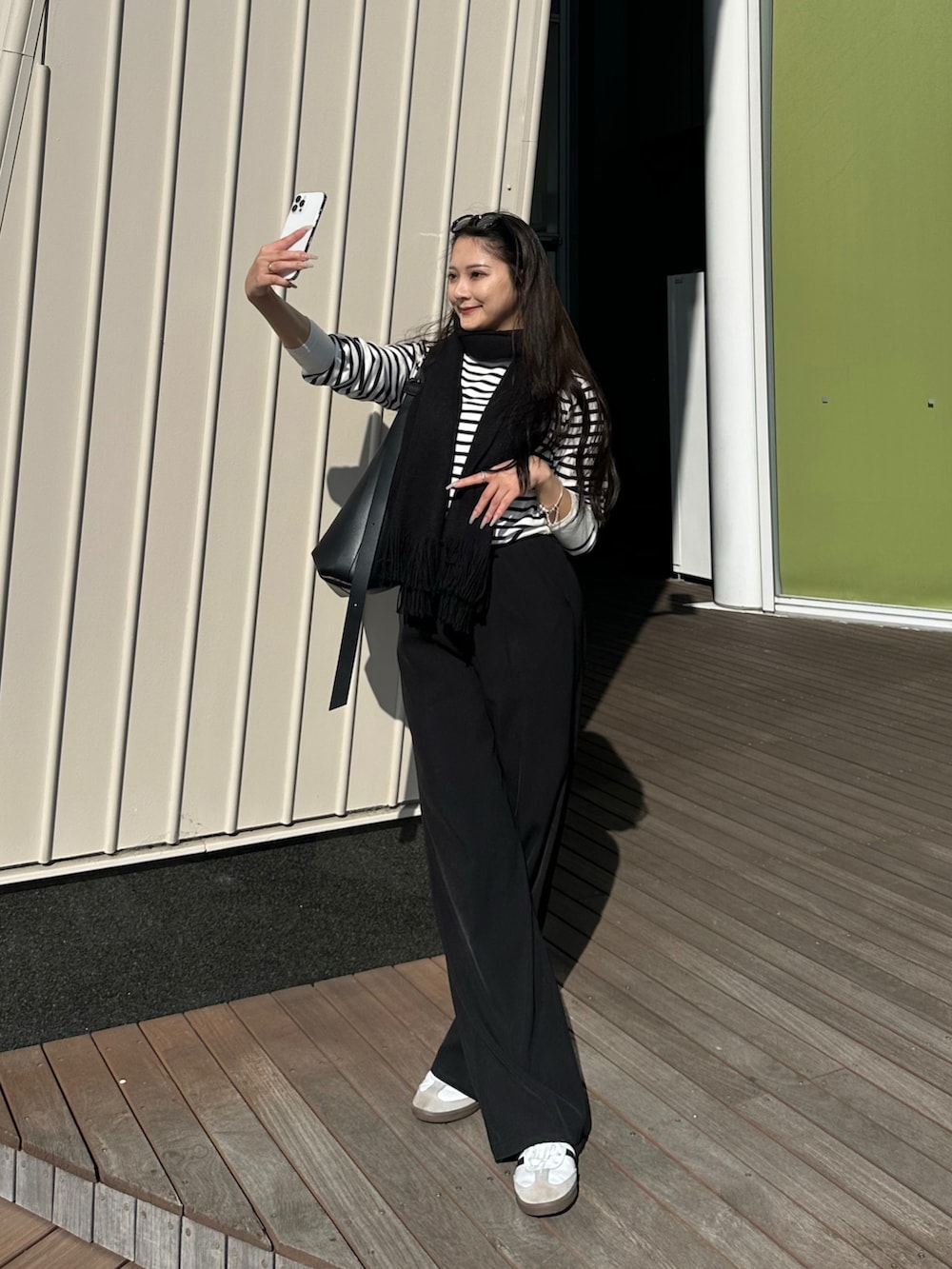 ブラック系のニット/セーター、ブラック系のショルダーバッグ、ブラック系のスラックスを着用したレディースの秋コーディネートの2枚目の写真