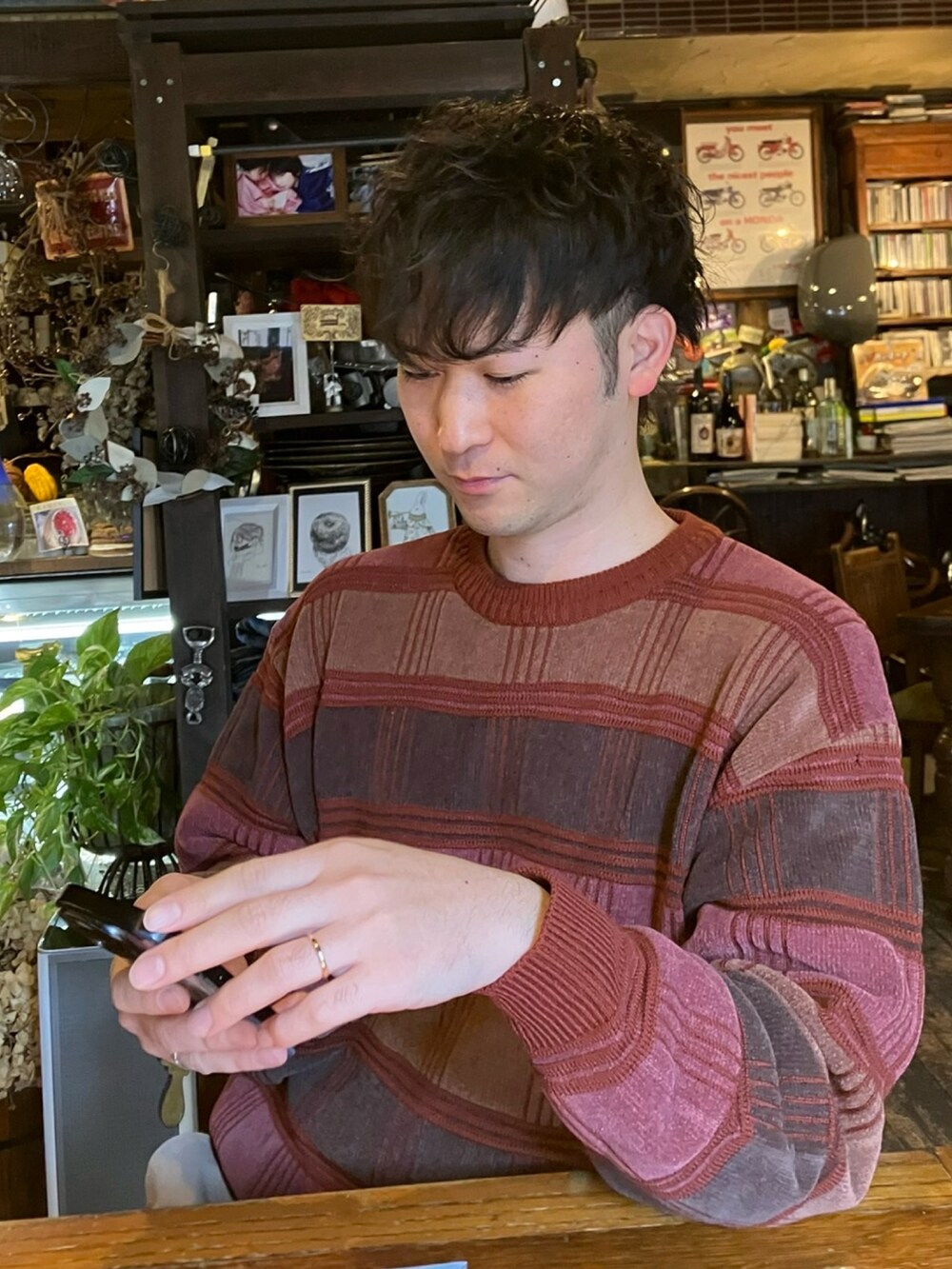 レッド系のニット/セーター、ベージュ系のパンツ、ブラック系のスリッポンを着用したメンズの冬コーディネートの2枚目の写真