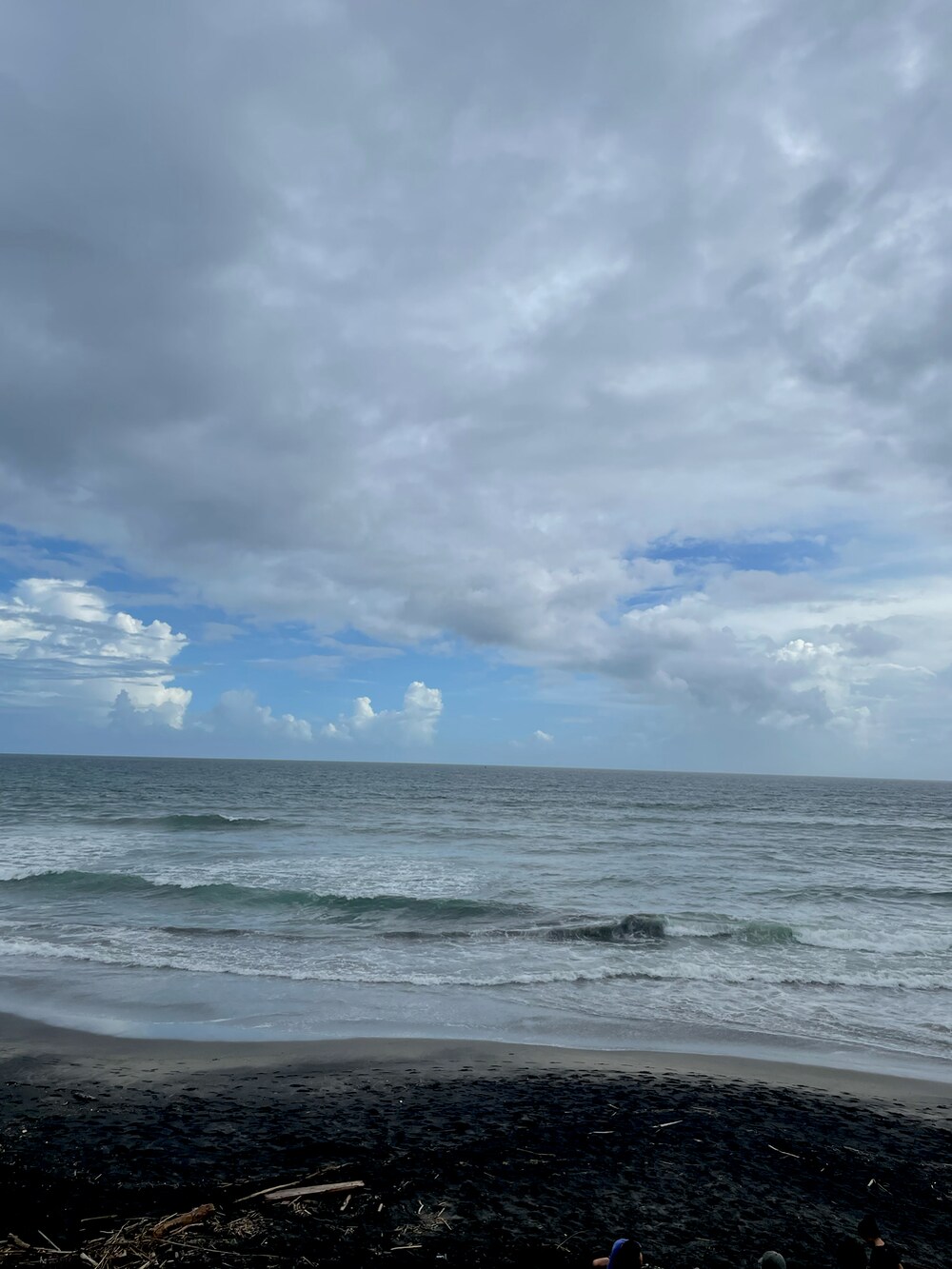 ブラック系のトップス、ベージュ系のかごバッグ、ブルー系のスニーカーを着用したレディースの夏コーディネートの2枚目の写真