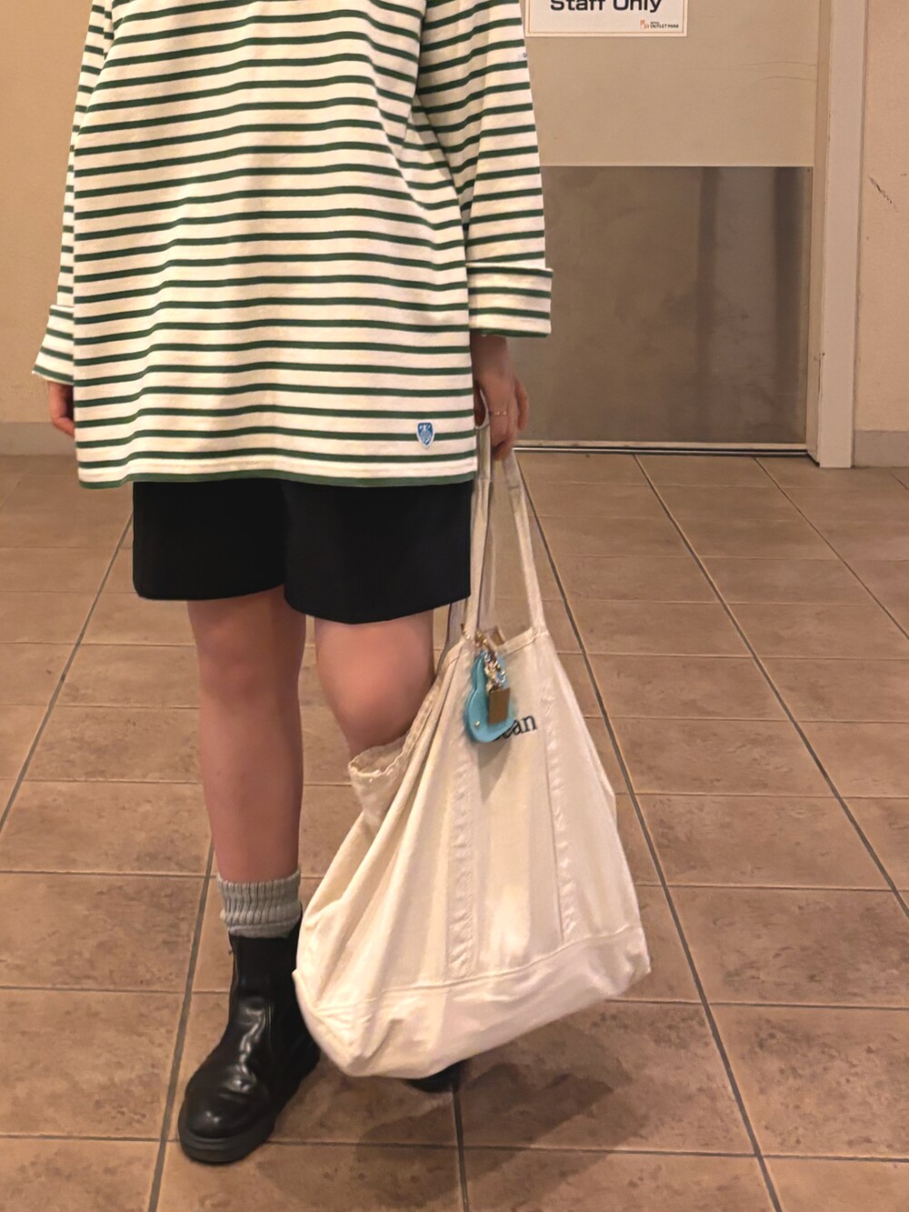 ホワイト系のトートバッグ、グリーン系のTシャツ/カットソー、ブラック系のその他パンツを着用したレディースの秋コーディネートの2枚目の写真