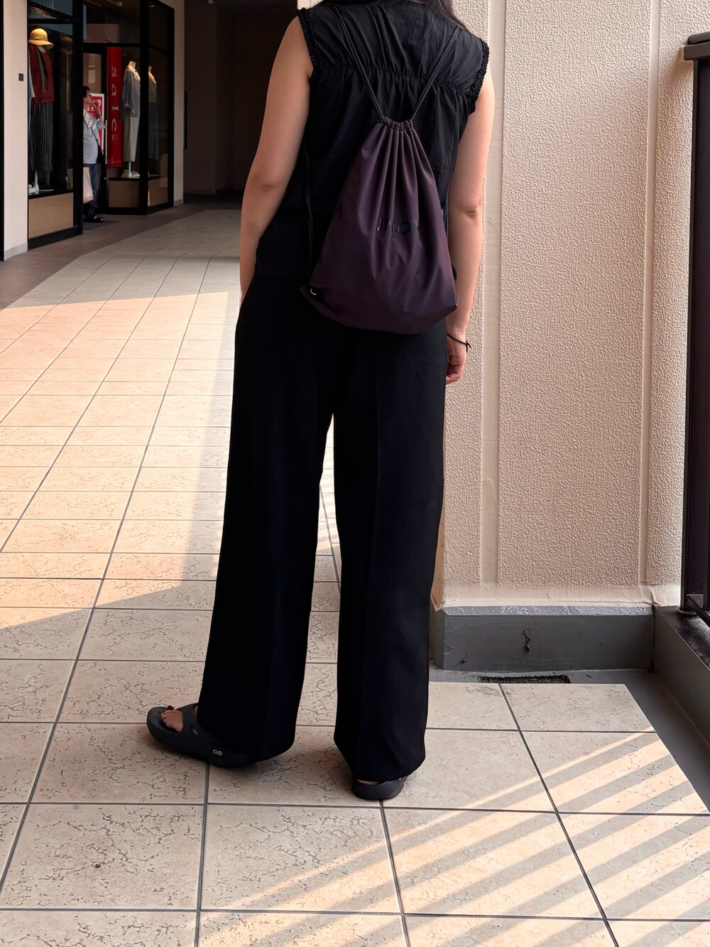 ブラック系のサンダル、パープル系のバックパック/リュックを着用したレディースの夏コーディネートの2枚目の写真