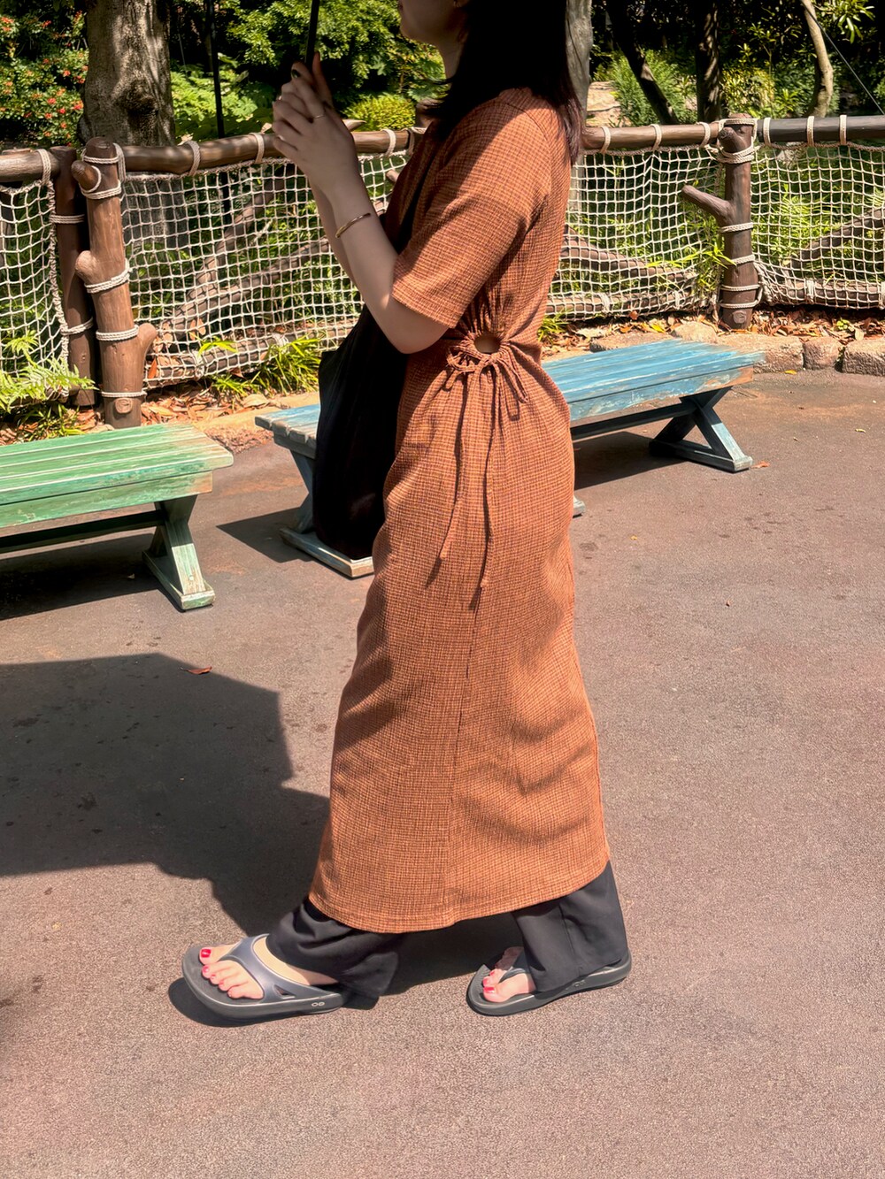 オレンジ系のワンピース、ブラック系のサンダルを着用したレディースの夏コーディネートの2枚目の写真