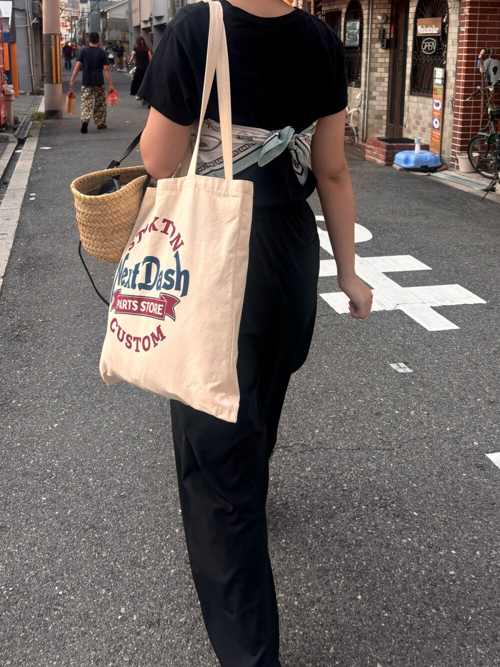 ベージュ系のかごバッグ、ブラック系のサンダル、ブラック系のパンツを着用したレディースの夏コーディネートの2枚目の写真