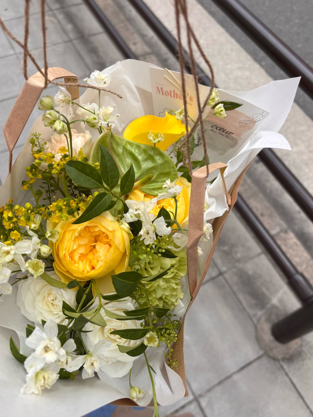 ホワイト系のトートバッグ、ブラック系のスニーカー、ブルー系のデニムパンツを着用したレディースの春コーディネートの2枚目の写真