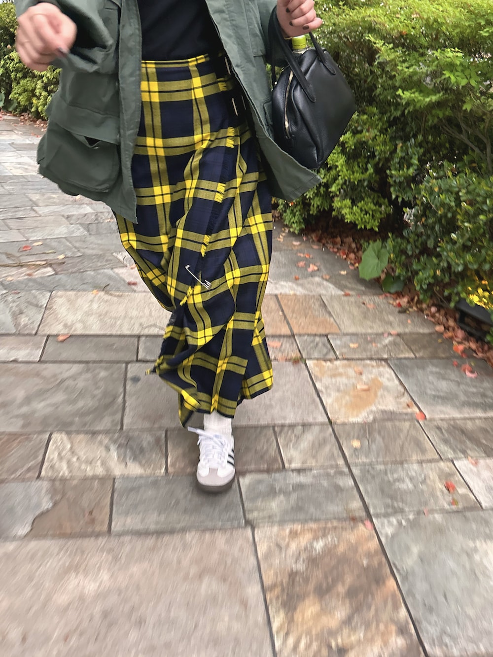 グリーン系のミリタリージャケット、イエロー系のスカート、ブラック系のボストンバッグを着用したレディースの春コーディネートの3枚目の写真