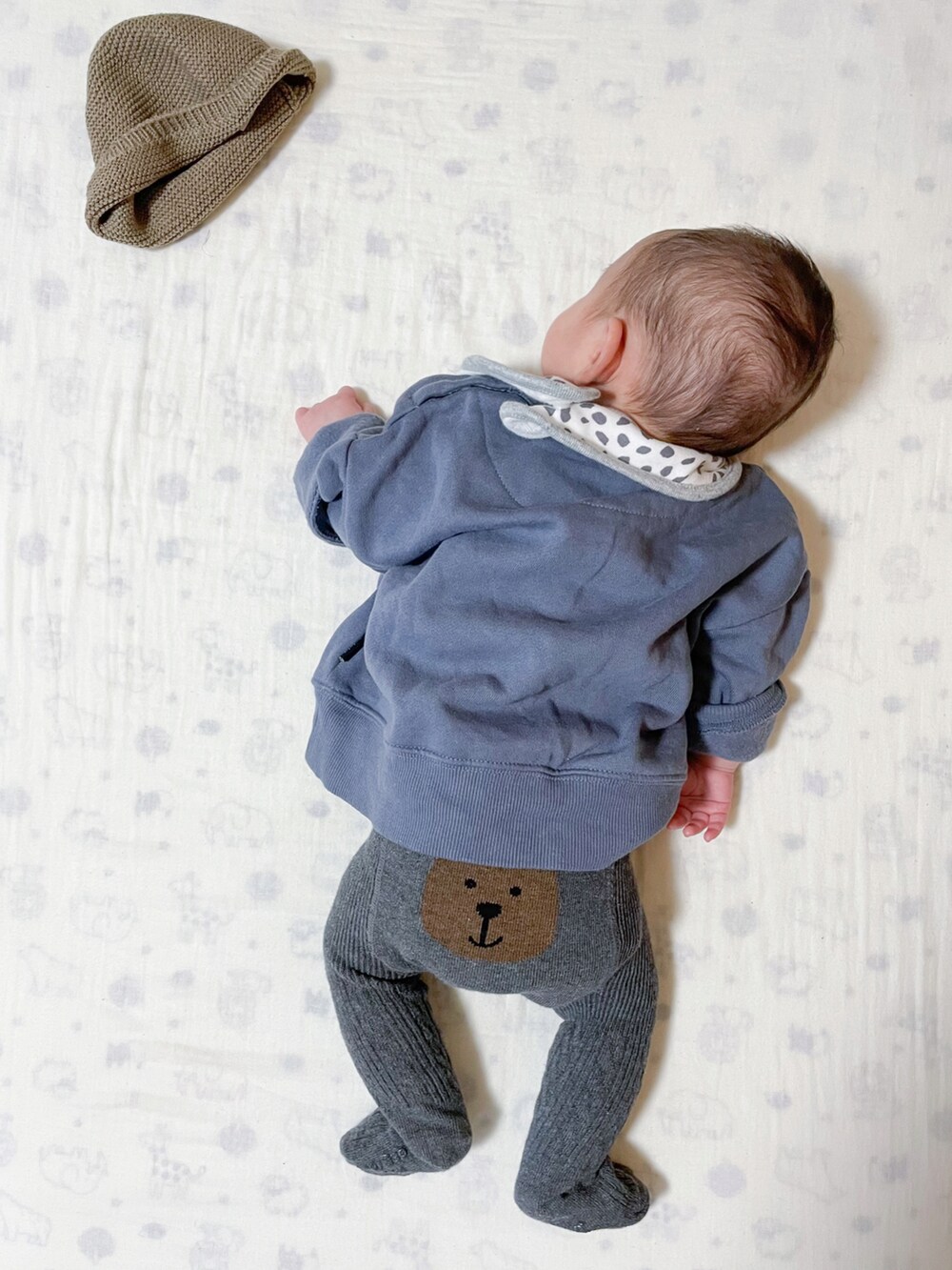 グリーン系の帽子、ブルー系のその他ベビーウェア、グレー系のベビーシューズ/ベビーソックスを着用したキッズの秋コーディネートの2枚目の写真