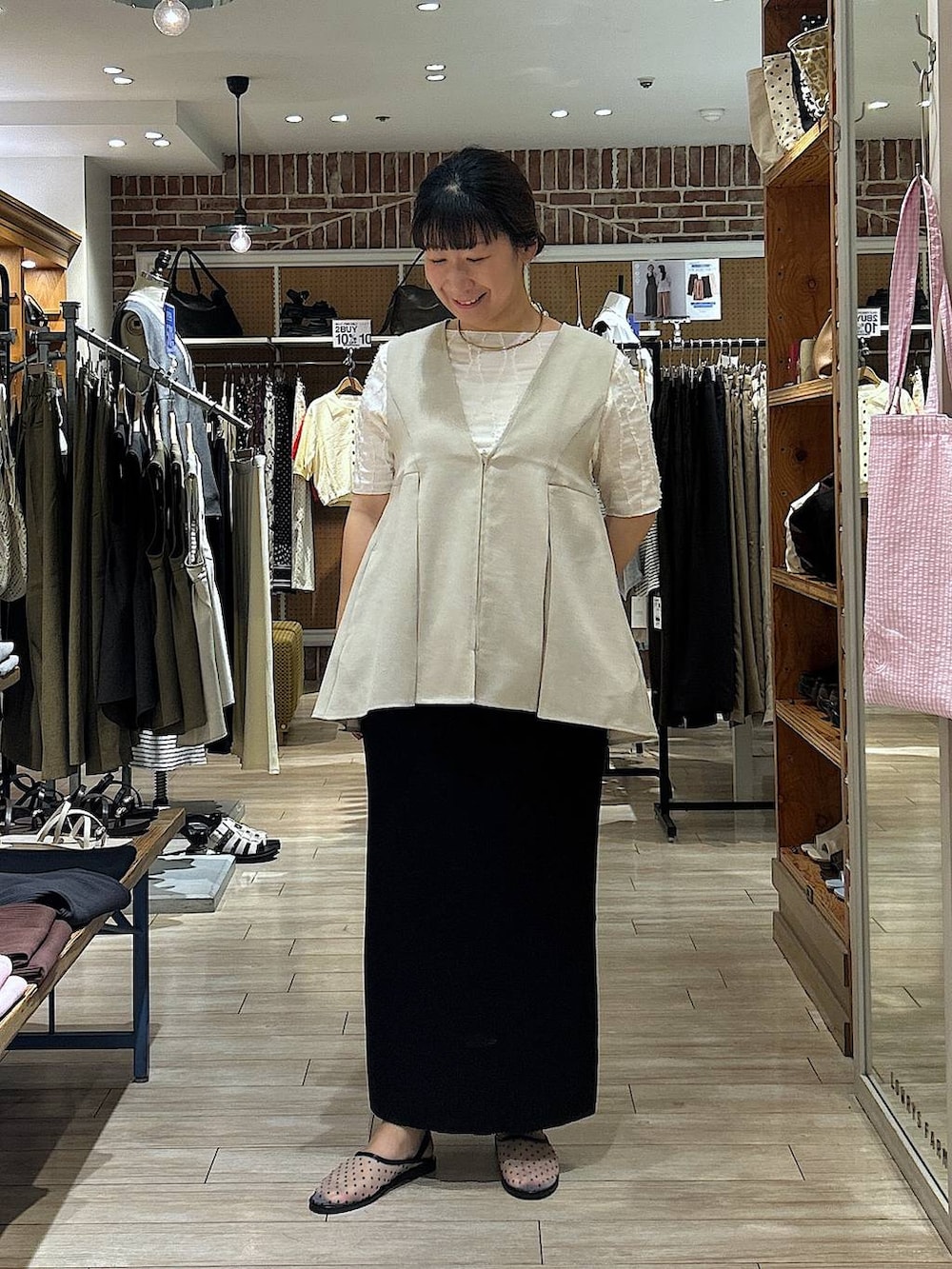 ブラック系のスカート、ホワイト系のTシャツ/カットソー、ベージュ系のベストを着用したレディースの夏コーディネートの5枚目の写真