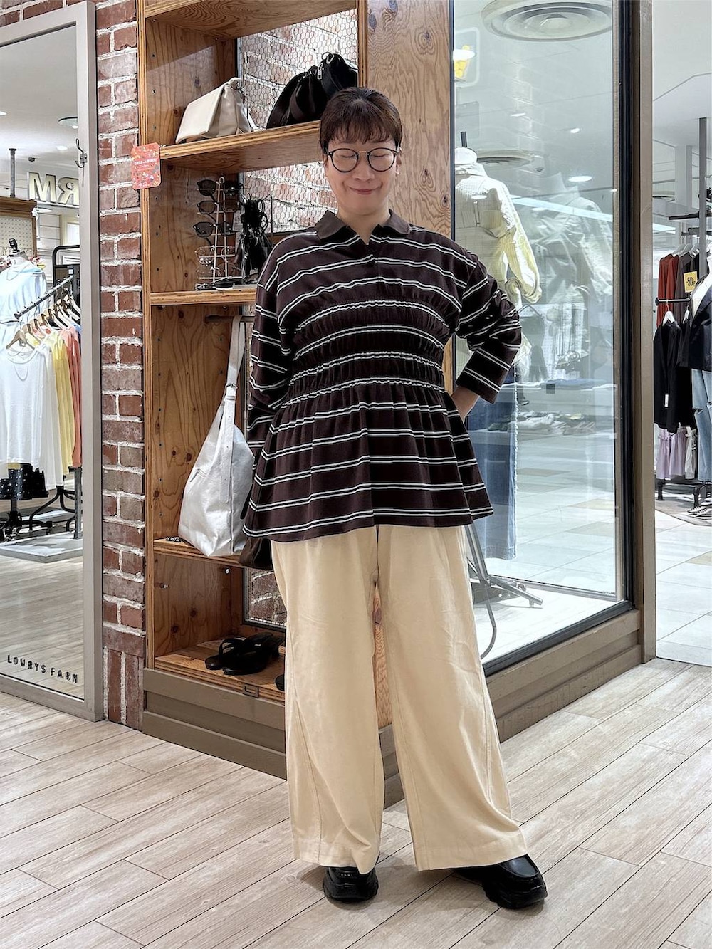 ブラウン系のポロシャツ、ホワイト系のデニムパンツ、ブラック系のローファーを着用したレディースの秋コーディネートの2枚目の写真