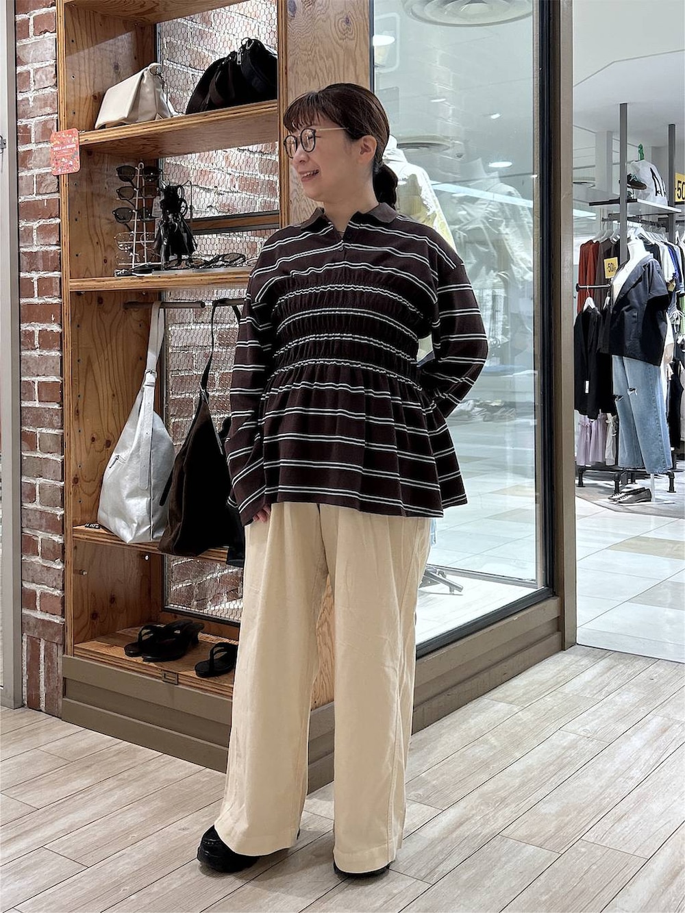 ブラウン系のポロシャツ、ホワイト系のデニムパンツ、ブラック系のローファーを着用したレディースの秋コーディネートの3枚目の写真