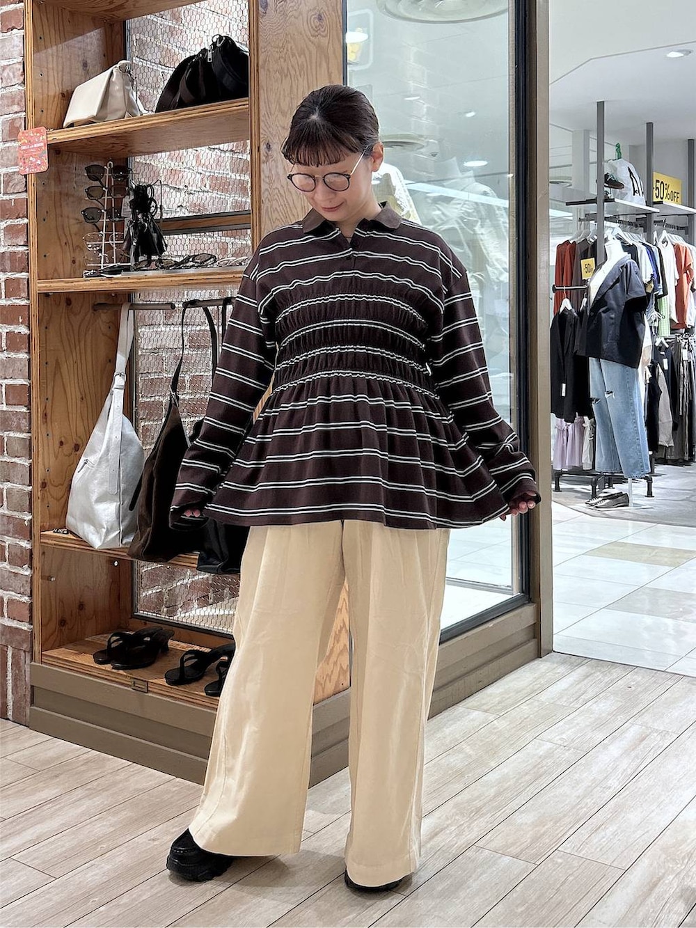 ブラウン系のポロシャツ、ホワイト系のデニムパンツ、ブラック系のローファーを着用したレディースの秋コーディネートの7枚目の写真