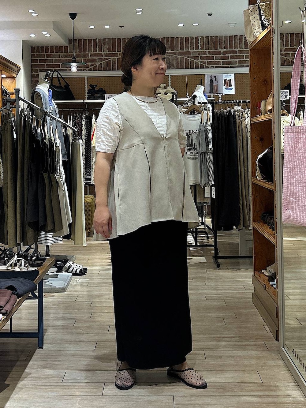 ブラック系のスカート、ホワイト系のTシャツ/カットソー、ベージュ系のベストを着用したレディースの夏コーディネートの2枚目の写真