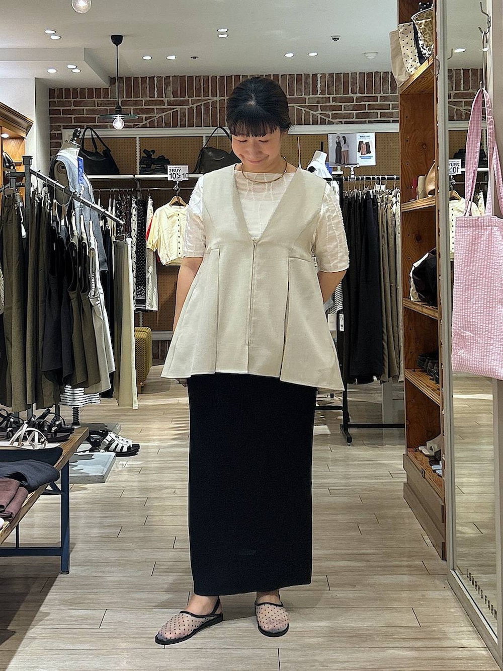 ブラック系のスカート、ホワイト系のTシャツ/カットソー、ベージュ系のベストを着用したレディースの夏コーディネートの3枚目の写真