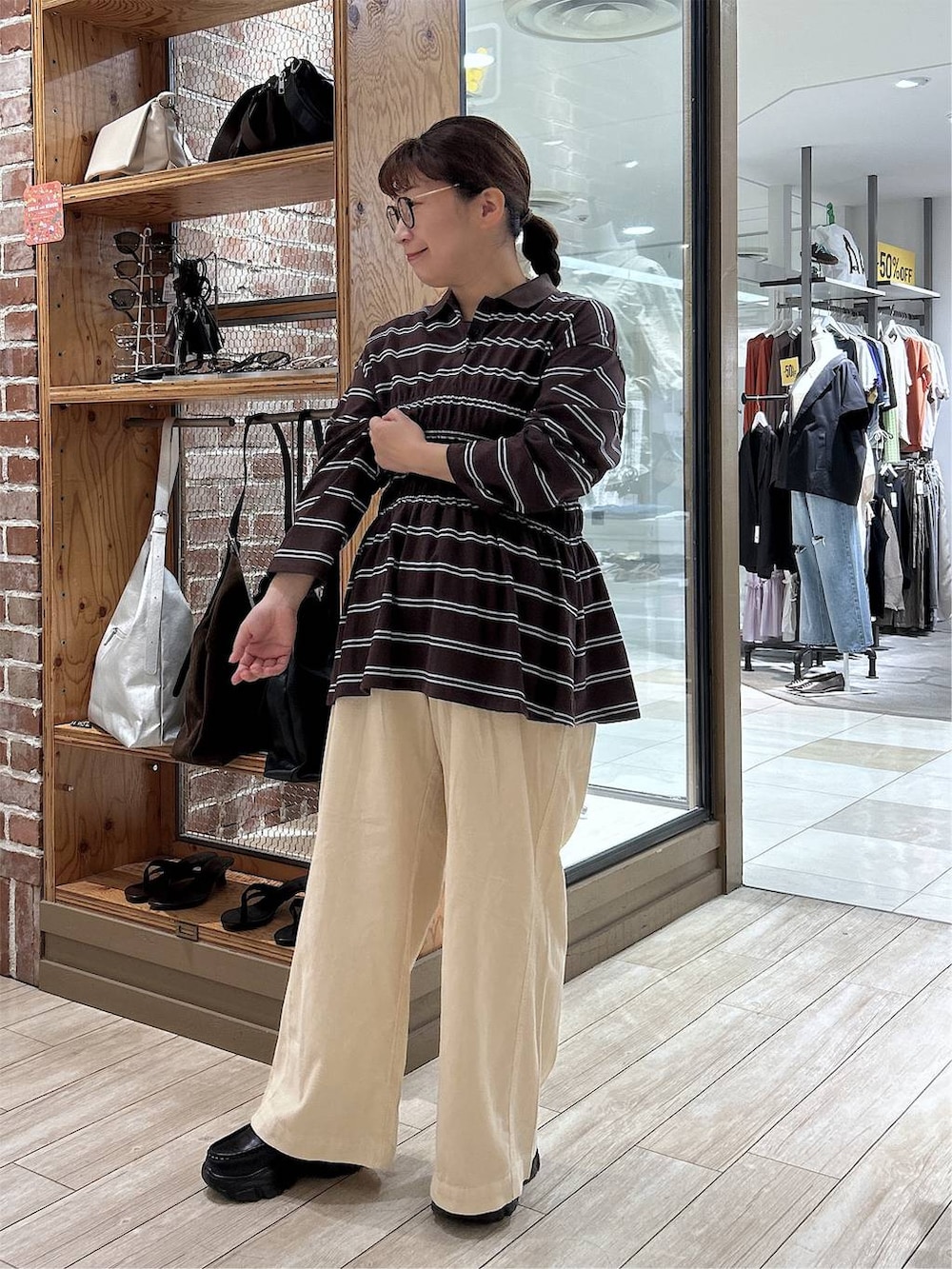 ブラウン系のポロシャツ、ホワイト系のデニムパンツ、ブラック系のローファーを着用したレディースの秋コーディネートの6枚目の写真
