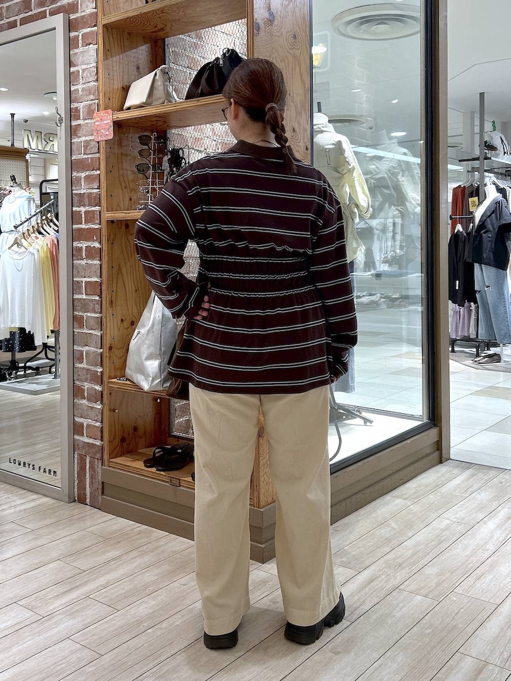 ブラウン系のポロシャツ、ホワイト系のデニムパンツ、ブラック系のローファーを着用したレディースの秋コーディネートの4枚目の写真