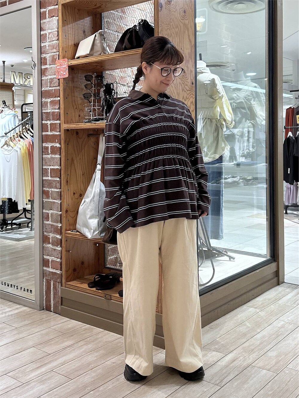 ブラウン系のポロシャツ、ホワイト系のデニムパンツ、ブラック系のローファーを着用したレディースの秋コーディネートの5枚目の写真