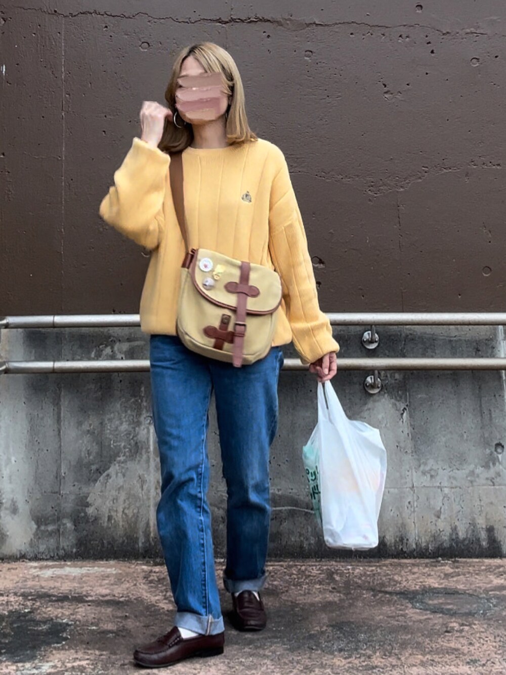 イエロー系のニット/セーター、ブルー系のデニムパンツ、ベージュ系のショルダーバッグを着用したレディースの春コーディネートの3枚目の写真