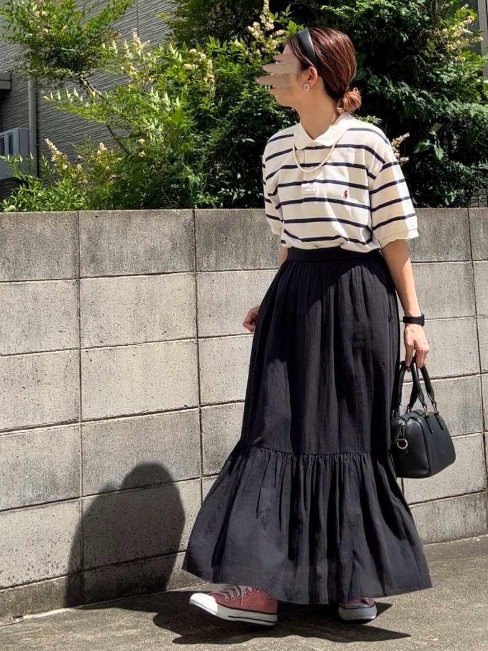 ホワイト系のポロシャツ、グレー系のスカート、ピンク系のスニーカーを着用したレディースの夏コーディネートの2枚目の写真