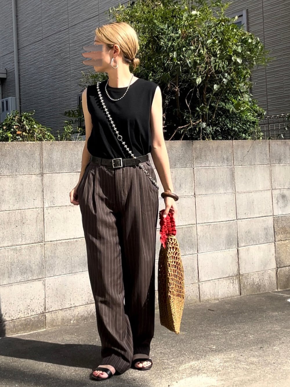 ブラウン系のスラックス、ベージュ系のトートバッグ、ブラック系のサンダルを着用したレディースの夏コーディネートの2枚目の写真