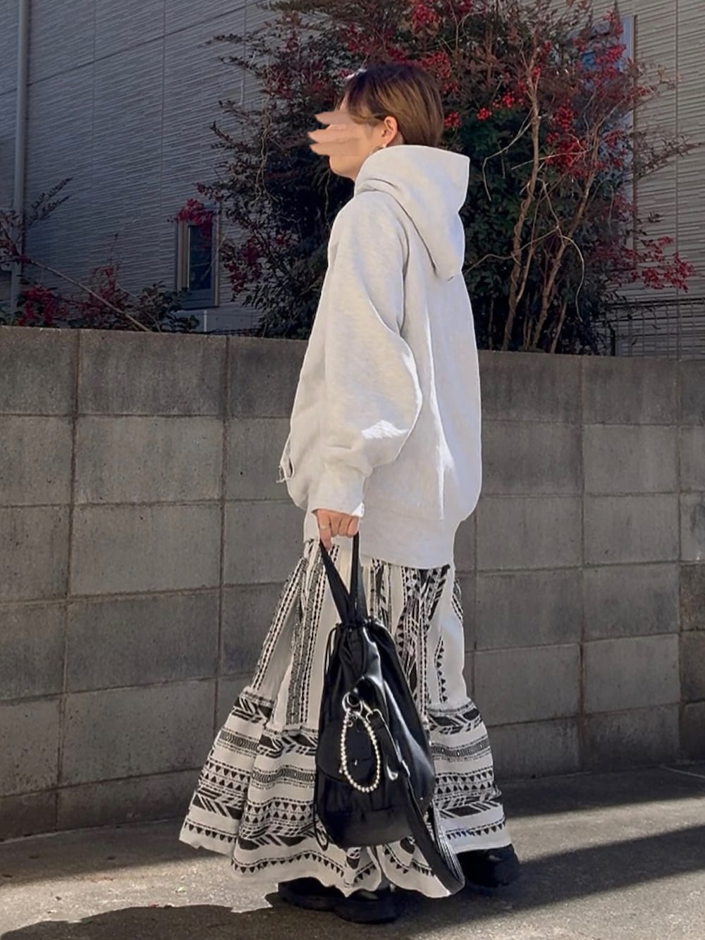 ブラック系のショルダーバッグ、ブラック系のスニーカー、グレー系のパーカーを着用したレディースの冬コーディネートの3枚目の写真