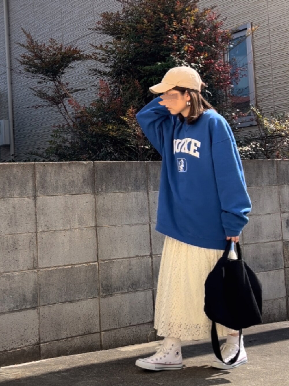 ブルー系のスウェット、ホワイト系のスカート、ホワイト系のスニーカーを着用したレディースの冬コーディネートの2枚目の写真