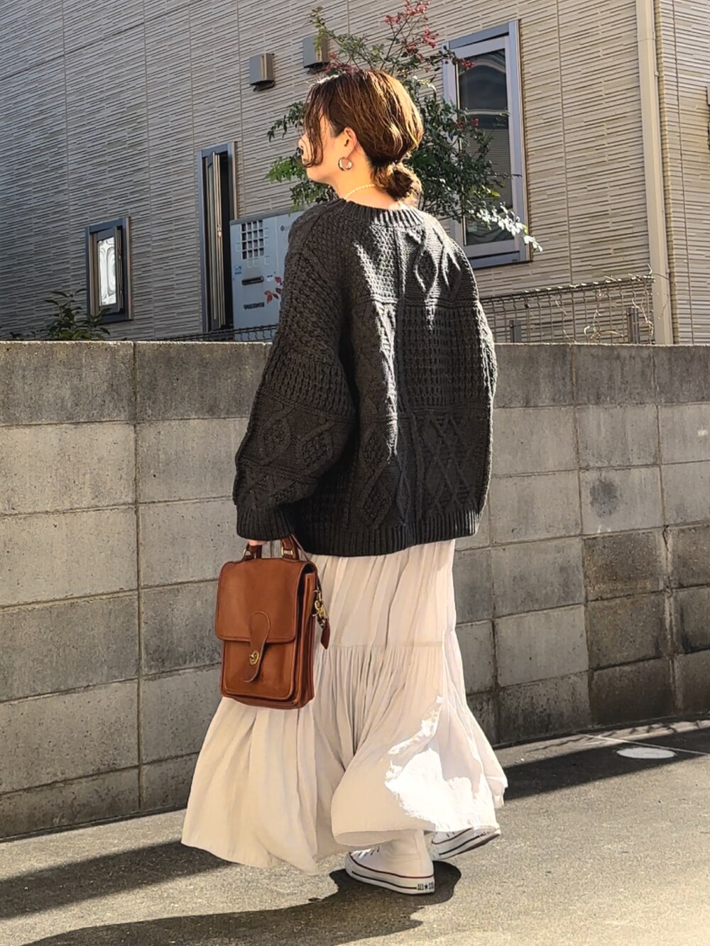 ブラック系のニット/セーター、グレー系のスカート、ブラウン系のショルダーバッグを着用したレディースの冬コーディネートの3枚目の写真
